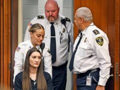 Madre en silla de ruedas acusada de asesinar a sus tres hijos es empujada ante el tribunal con una cruz alrededor del cuello después de que un intento de suicidio la dejara paralizada